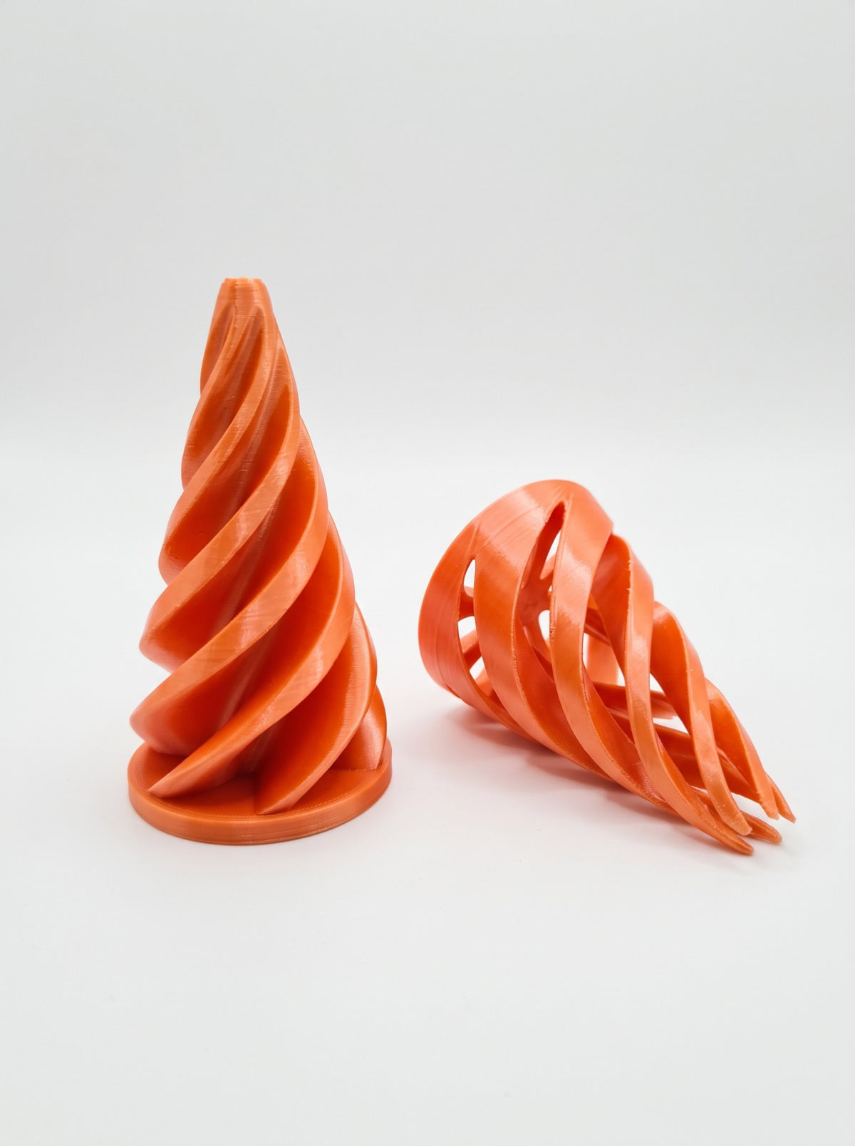Conos espiral 3D naranjas, uno de pie y otro comprimido